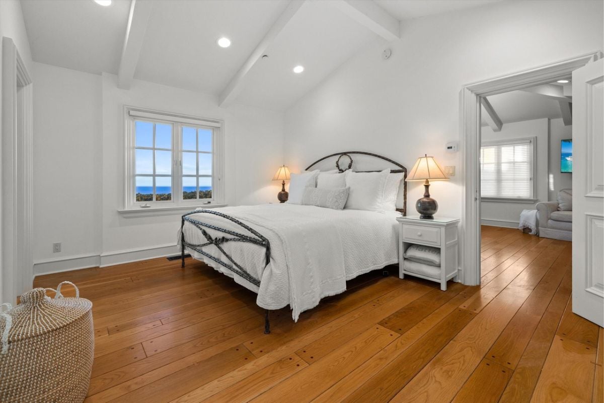 A bedroom with a bed, nightstand, lampshade, and window.