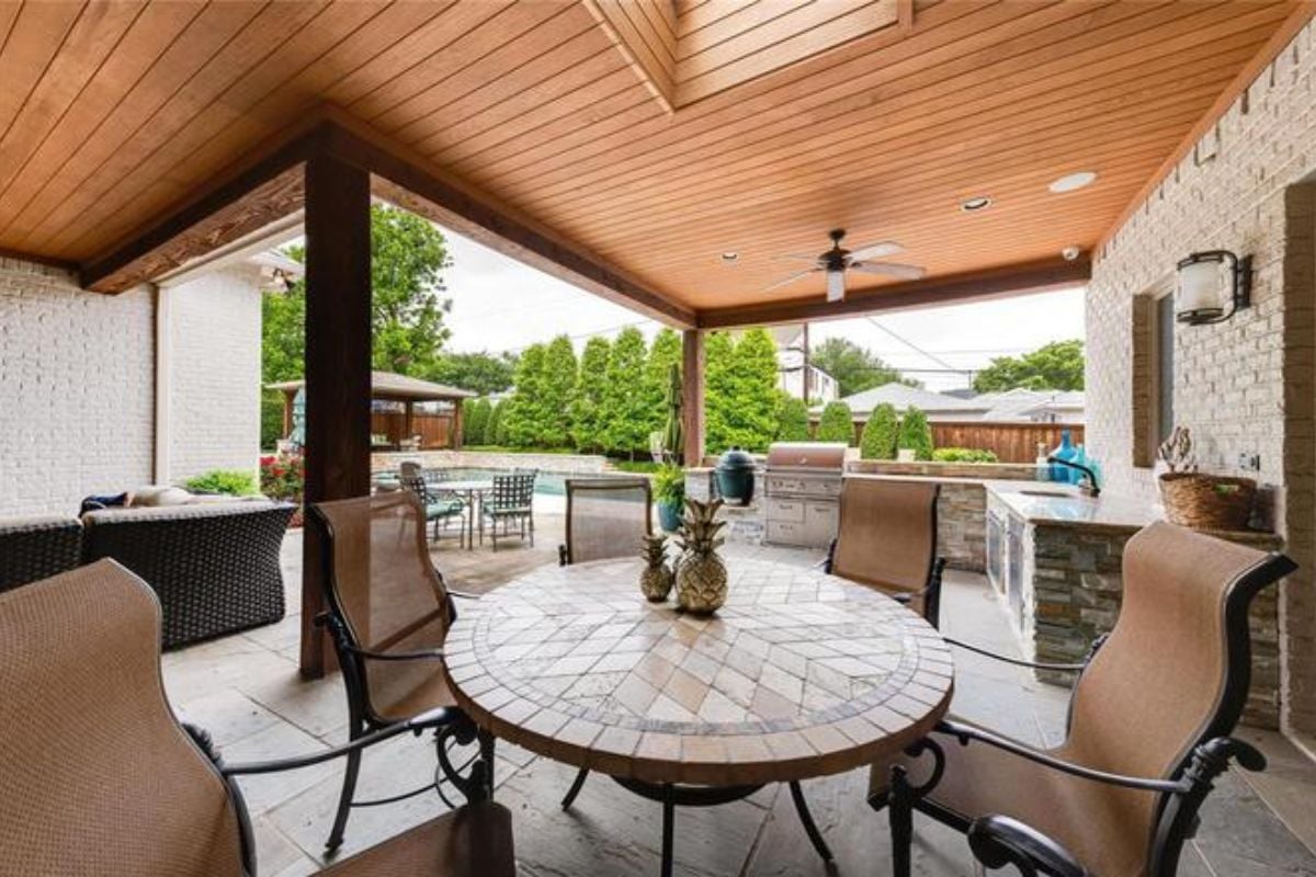 A porch with a table surrounded by chairs.
