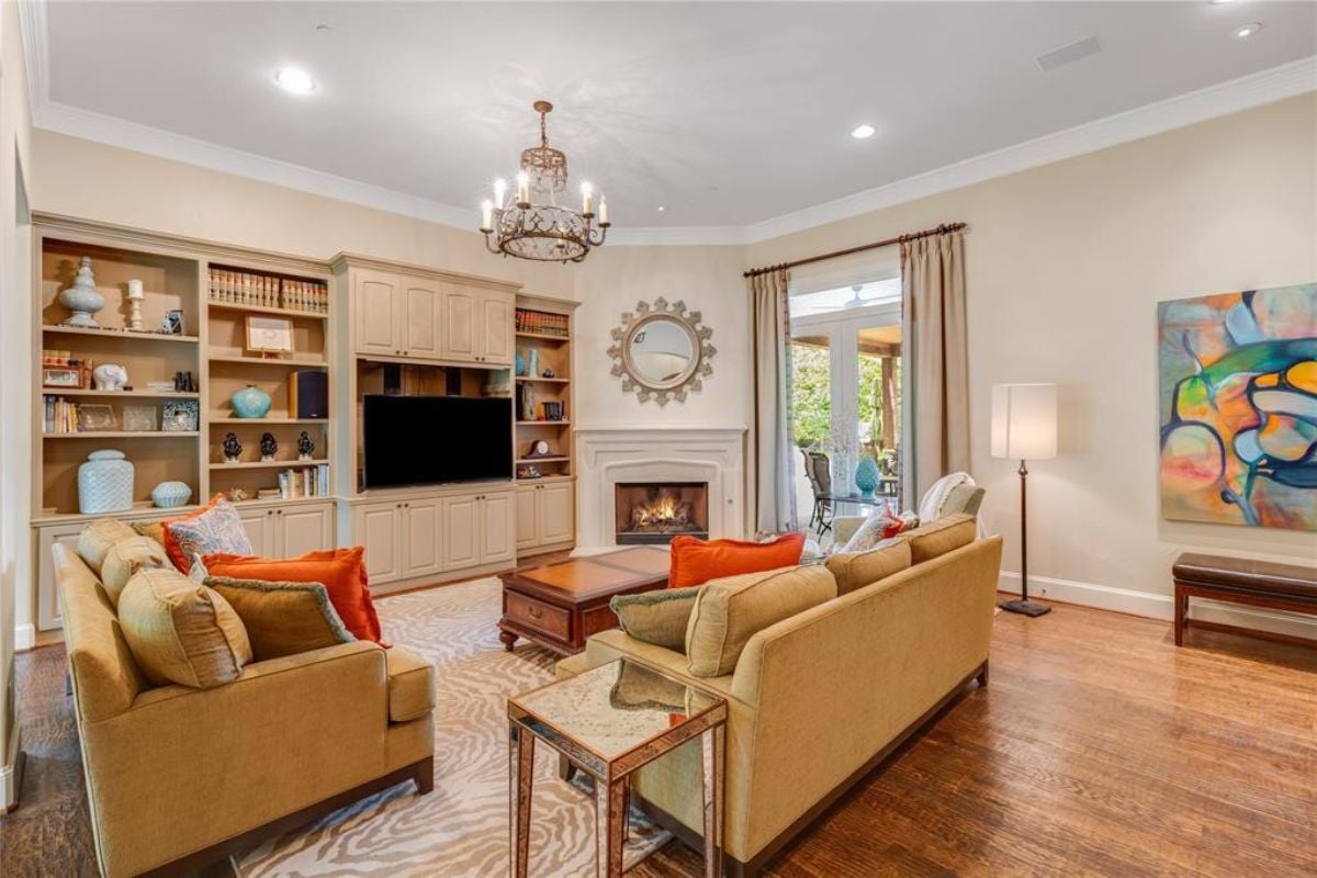 A living room with a fireplace, TV, shelves, cabinets, a painting, a couch, and a center table.
