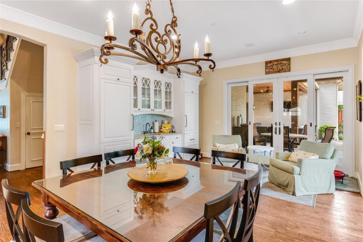 A dining area with a chandelier and a table surrounded by chairs.