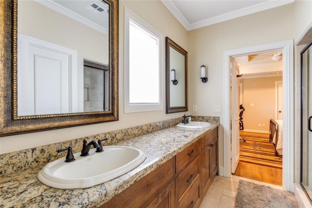 A bathroom with a countertop, sinks, mirrors, and drawers.