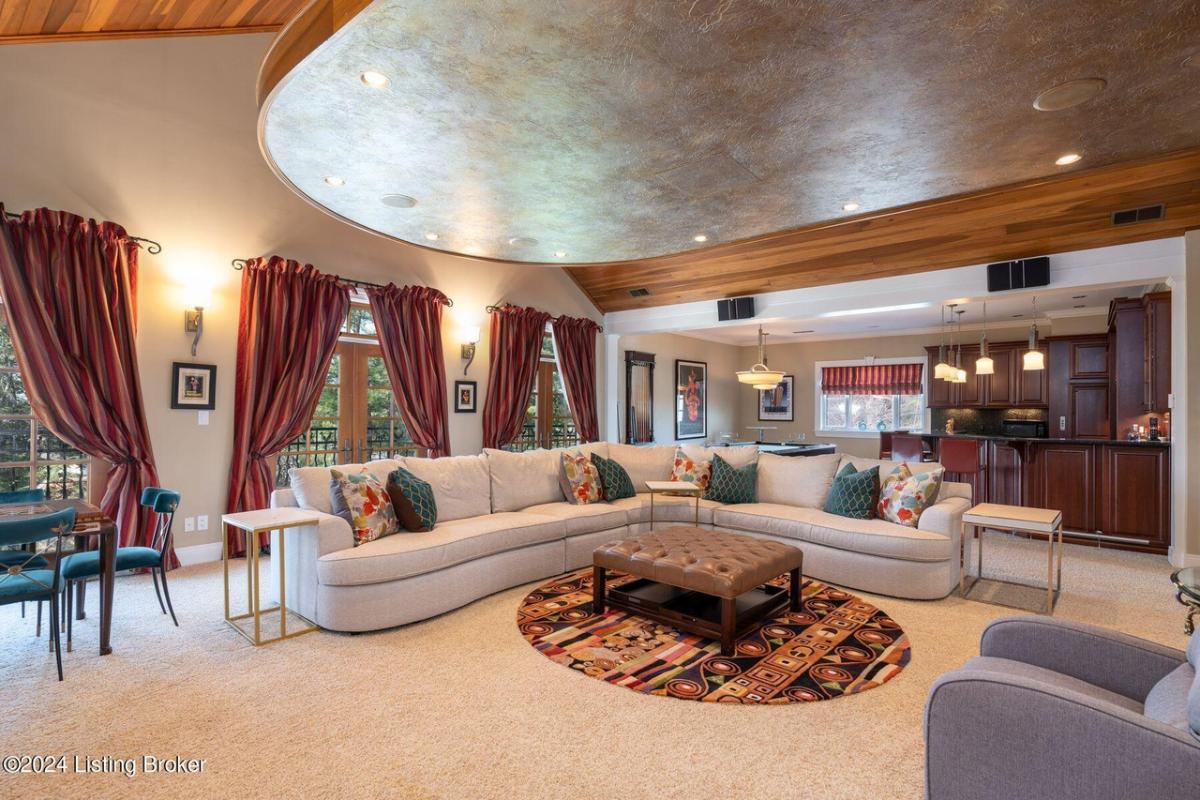 Living room with carpet flooring, couches and custom lighting.