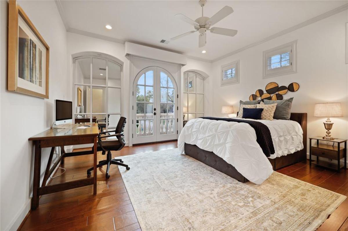 Bedroom with hardwood floors, desk and glass doors.