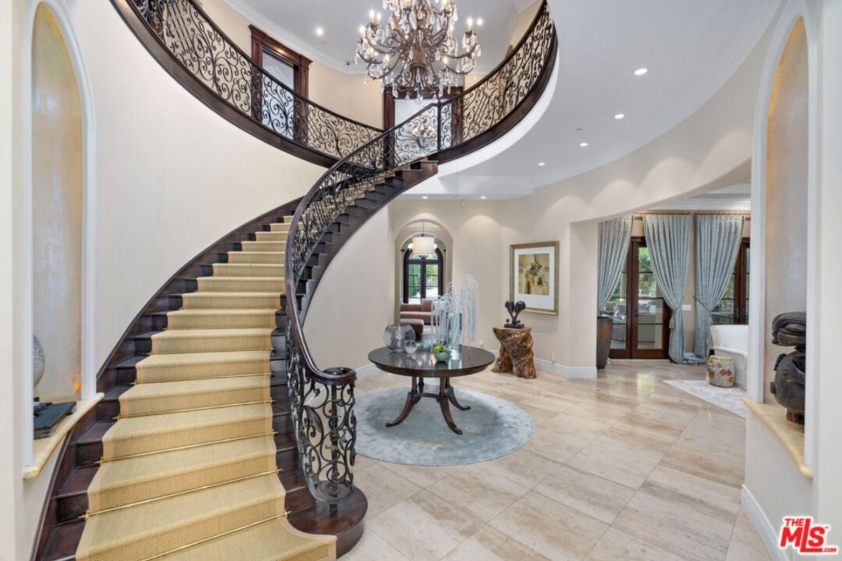 A foyer with a staircase, tiled floor, and table.