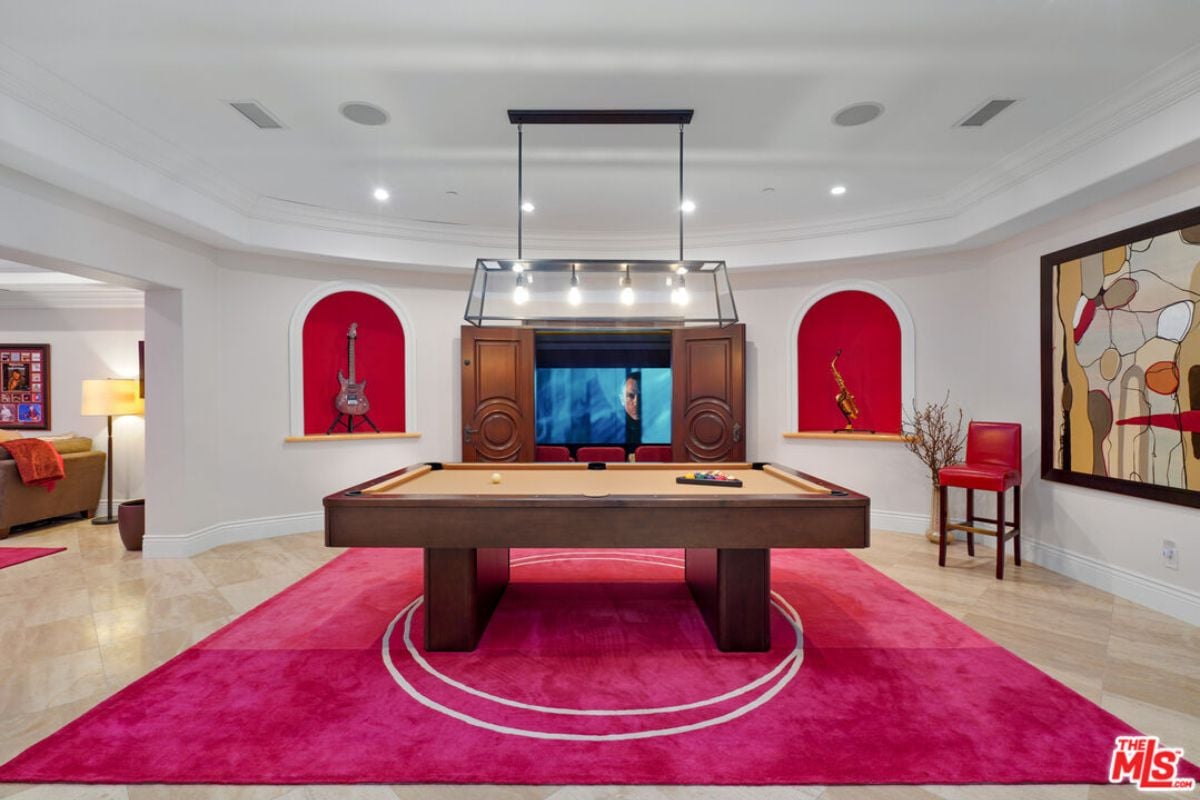 A game room with a painting, rug, chair, and pool table.