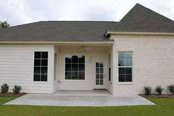 Left view showcasing the covered porch that transitions to a concrete patio.