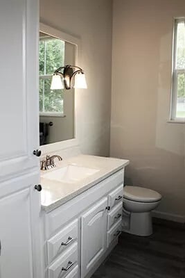 Primary bathroom with a toilet and a white vanity attached with a linen closet.