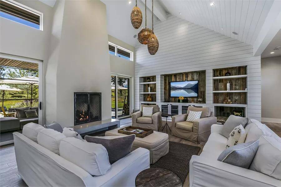 Living room with sectional sofas, skirted chairs, and a fireplace under a vaulted ceiling.
