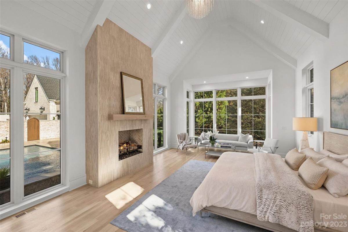 Bedroom with hardwood floor, a chandelier and a fireplace.