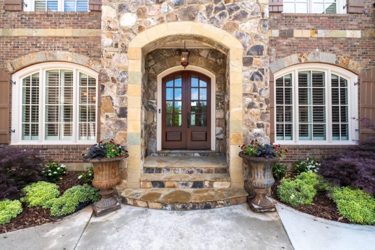 A front entry with plants and a brick wall.