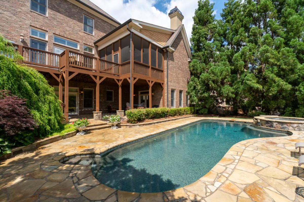 A swimming pool with a jacuzzi surrounded by plants and trees.