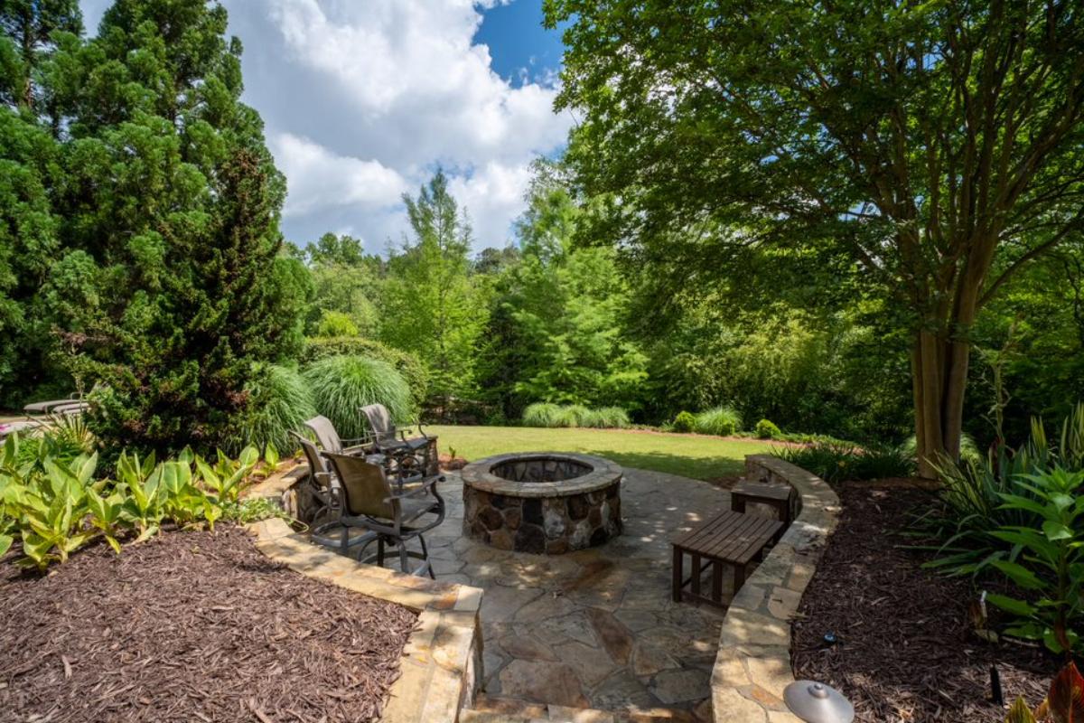 A patio with a fire pit, chairs, and a bench.