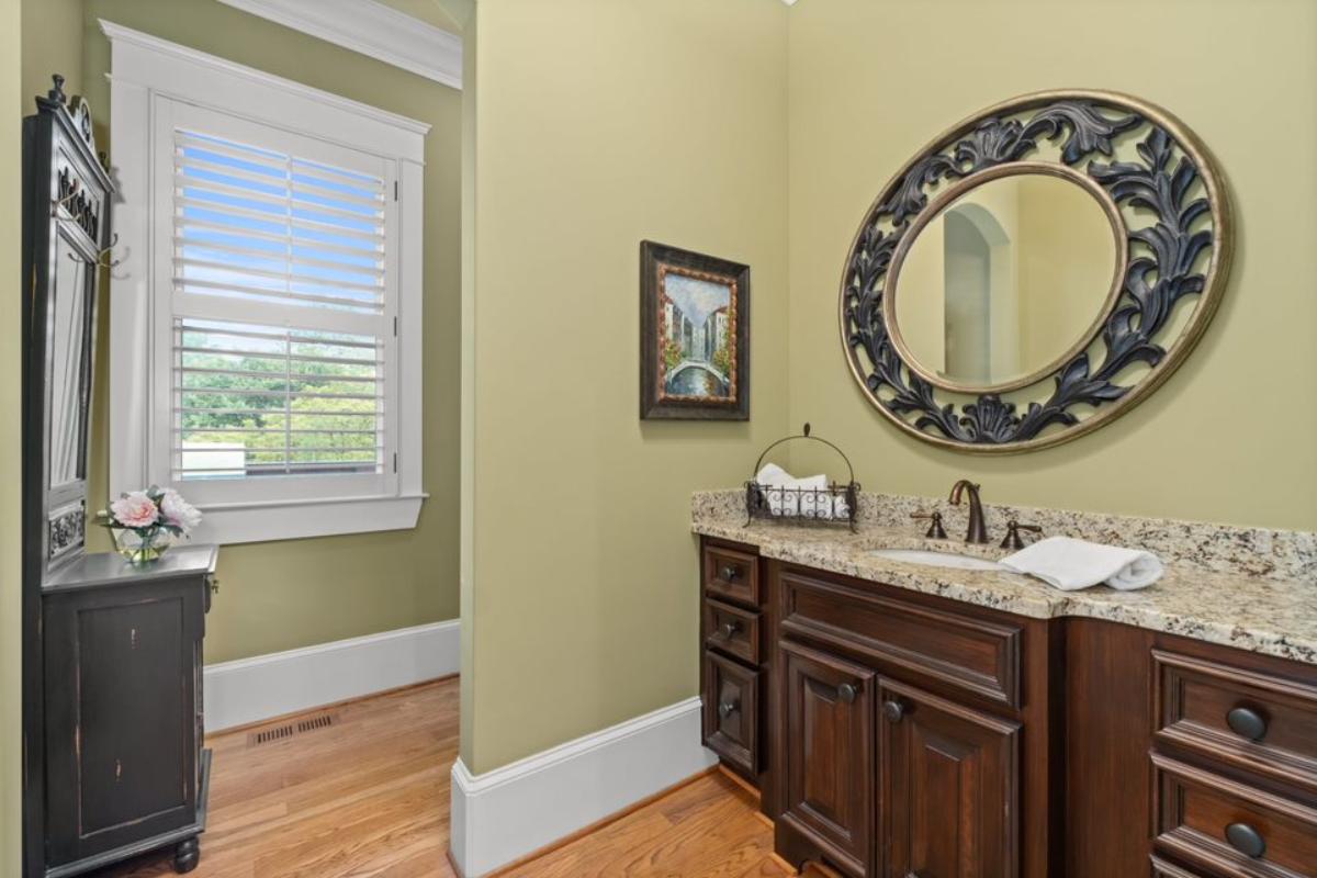 A bathroom with a vanity, cabinets, and a mirror.
