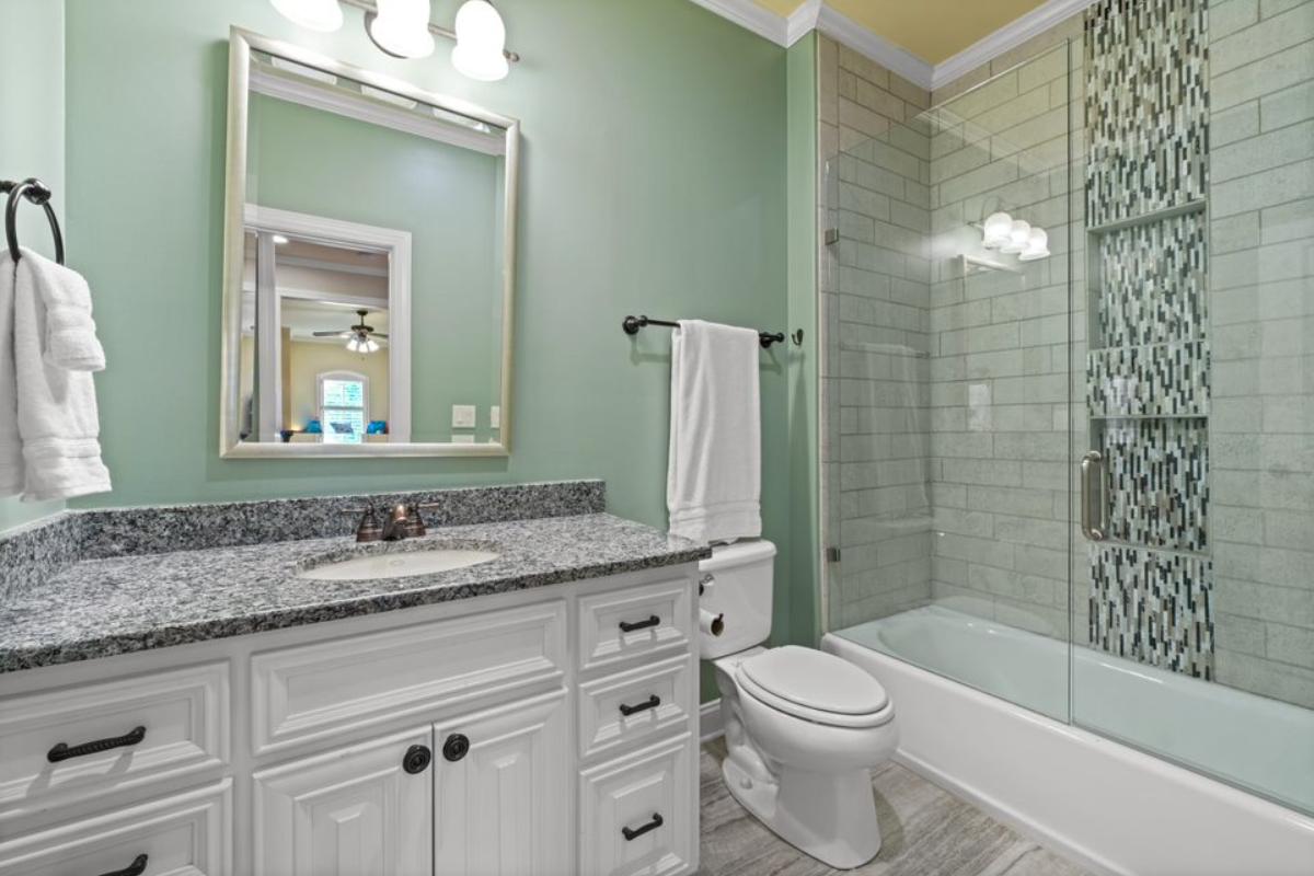 A bathroom with a vanity, cabinets, mirror, toilet, and bathtub.