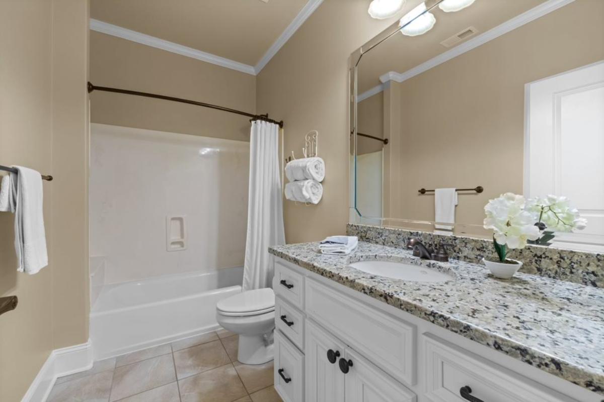 A bathroom with a vanity, cabinets, mirror, toilet, and bathtub.