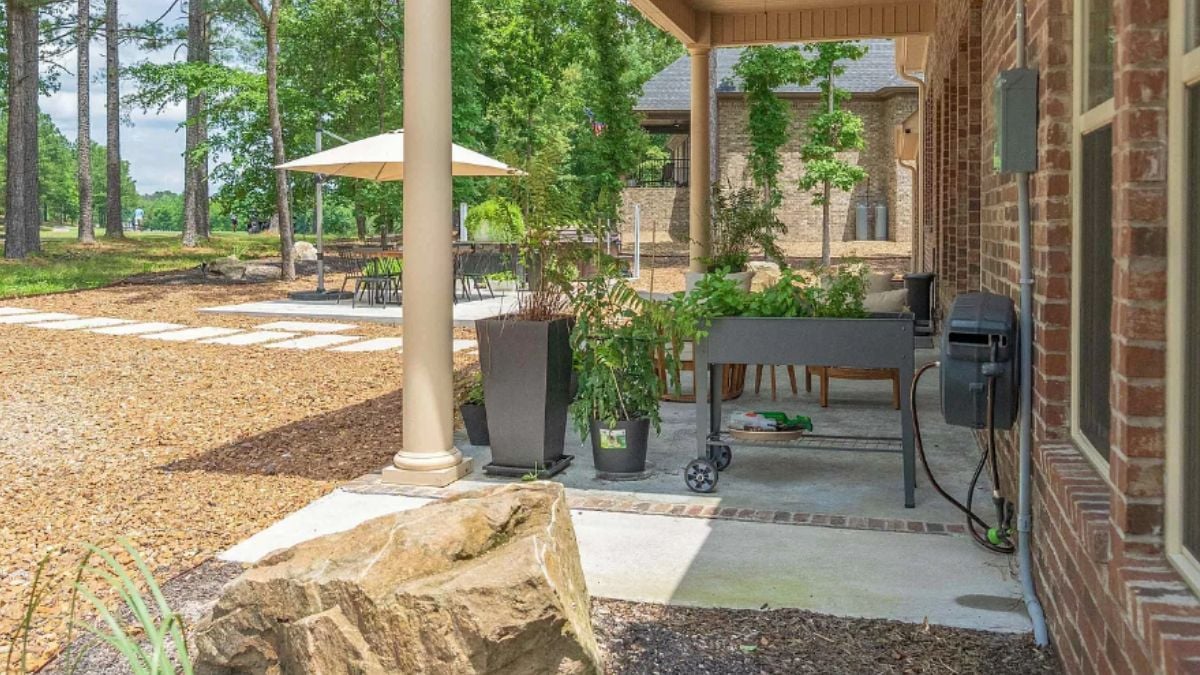 A porch with chairs, a table, and plants.