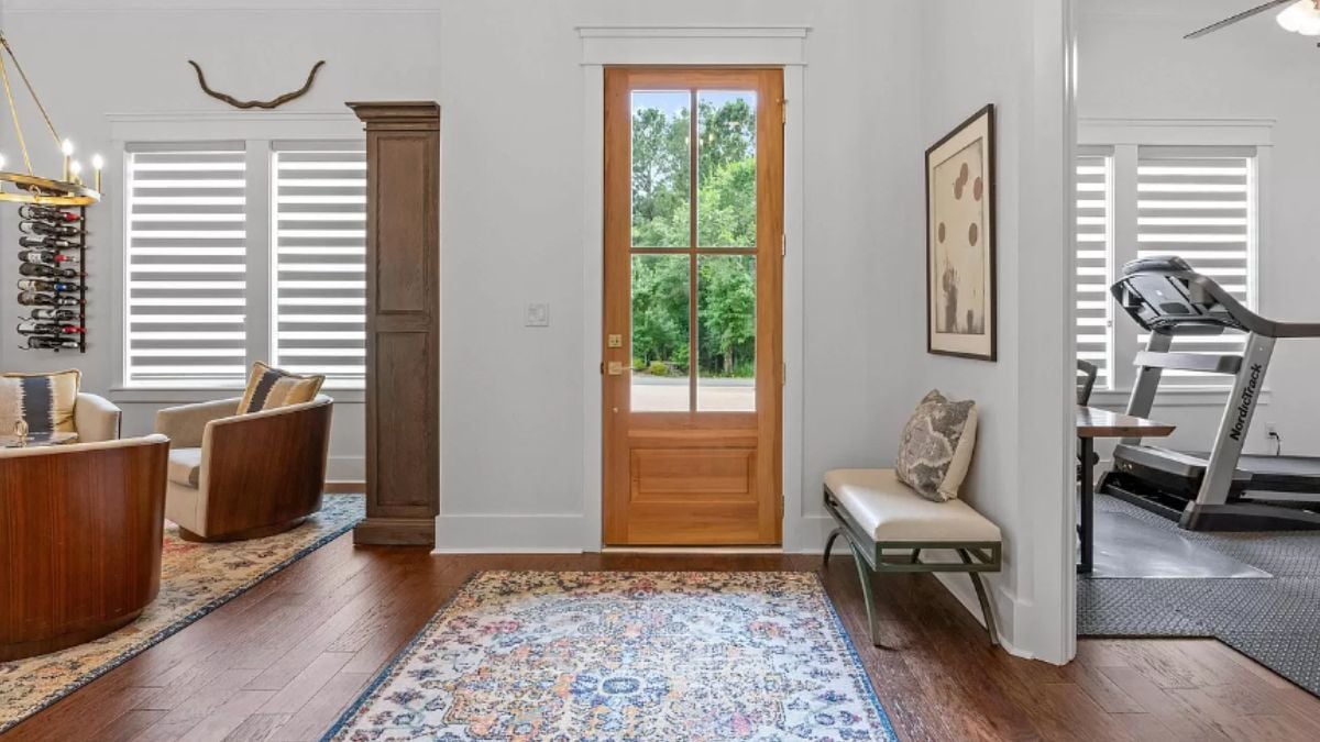 A foyer with a wooden floor, a rug, and a bench.