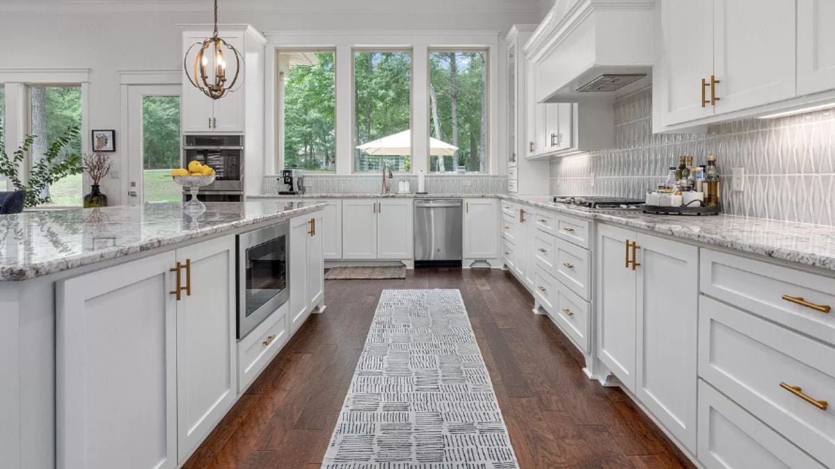 A kitchen with countertops, a window, cabinets, and kitchen appliances.