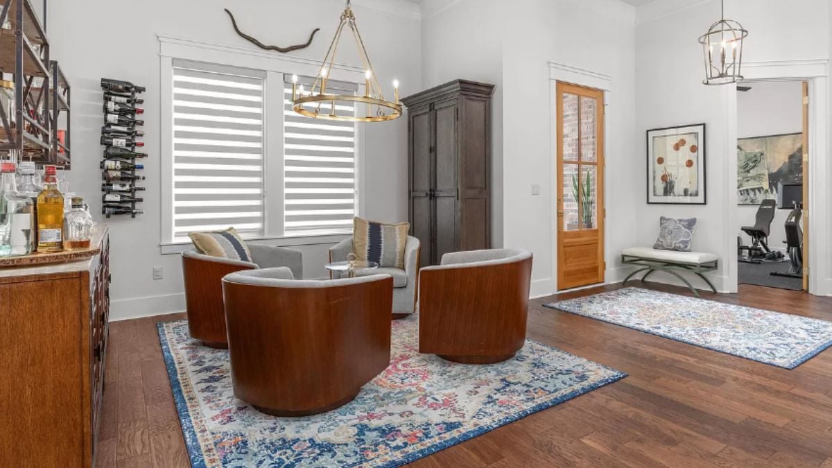 A bar with a countertop, wine racks, a rug, and a center table surrounded by chairs.