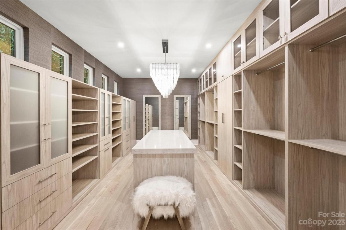 Walk-in closet with shelves, cabinets and a chandelier.