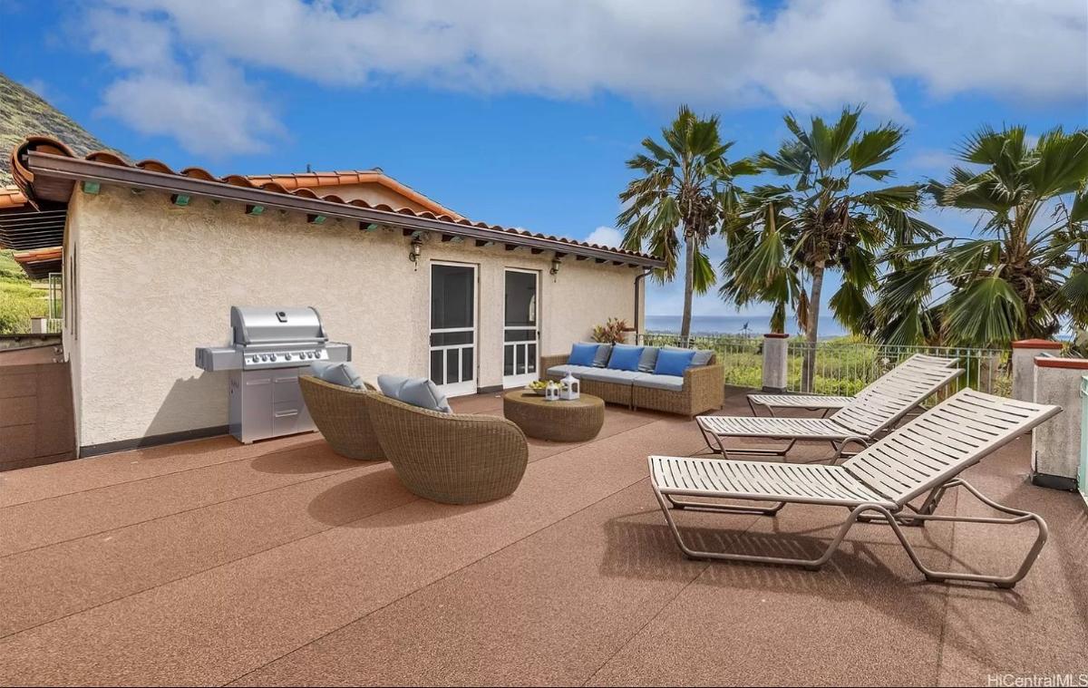 Balcony with lounge chairs and grill area.