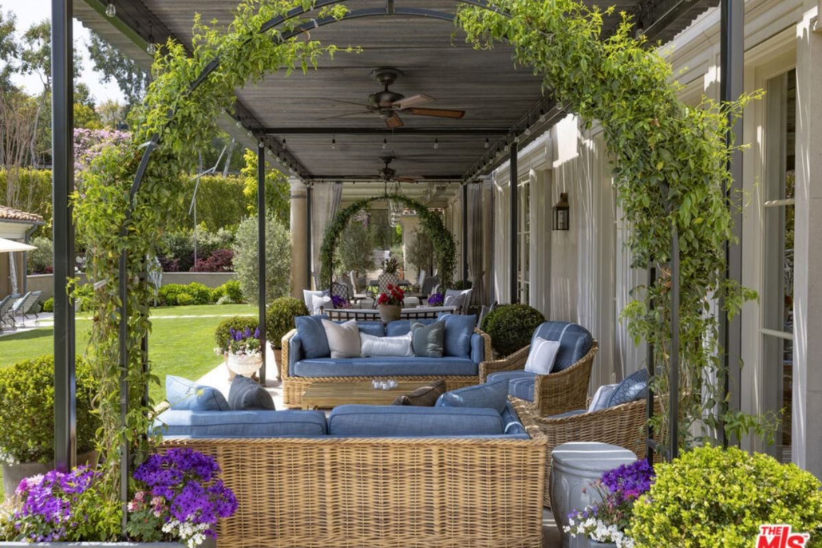 A porch with couches, plants, and a ceiling fan.