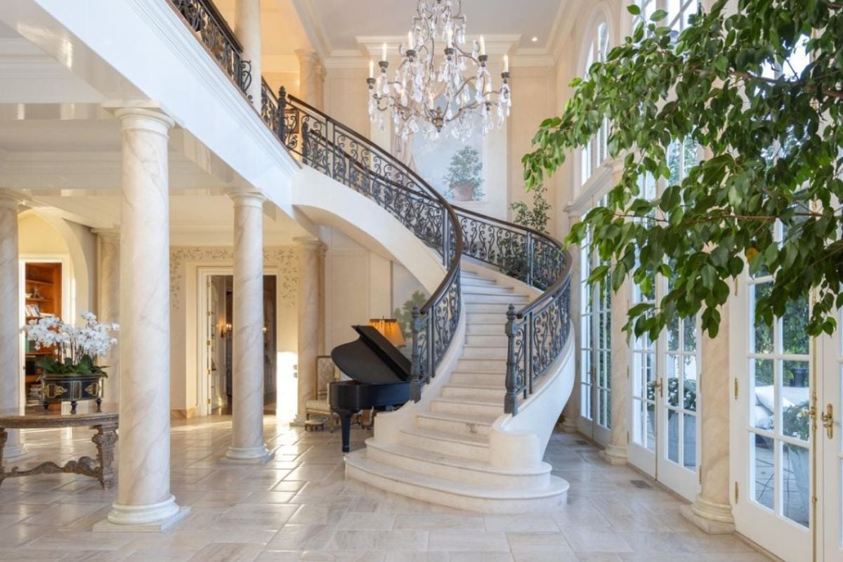 A foyer with tiled floor, chandelier, houseplant, and staircase.