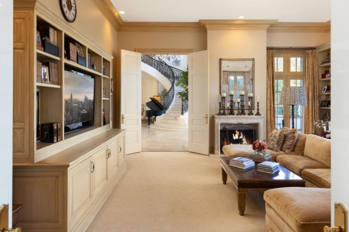 A living room with cabinets, shelves, TV, fireplace, couch, and center table.