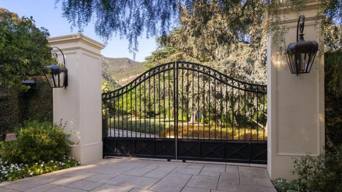 A front gate entry with a metal gate and plants.