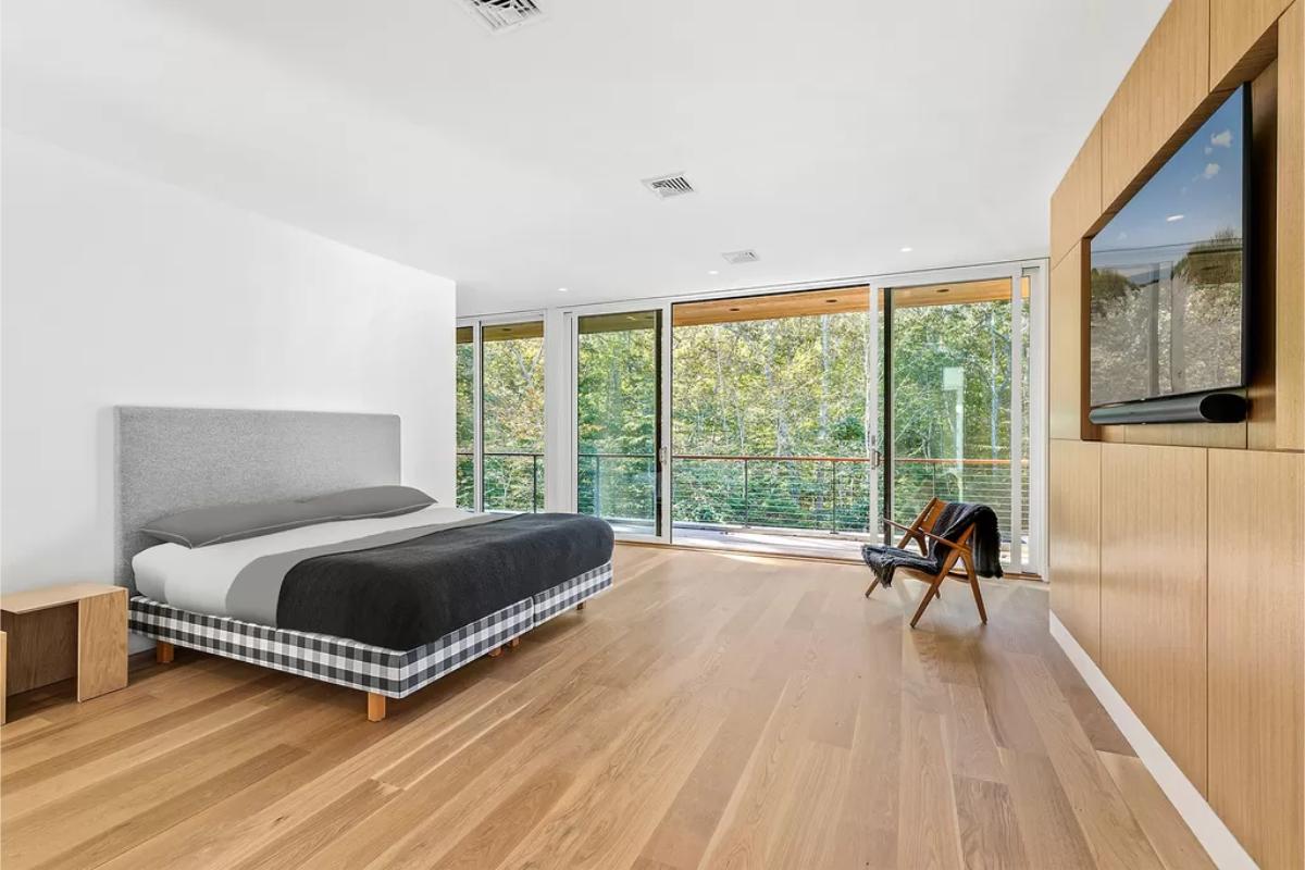 Bedroom with hardwood floor, a large bed and sliding glass doors.