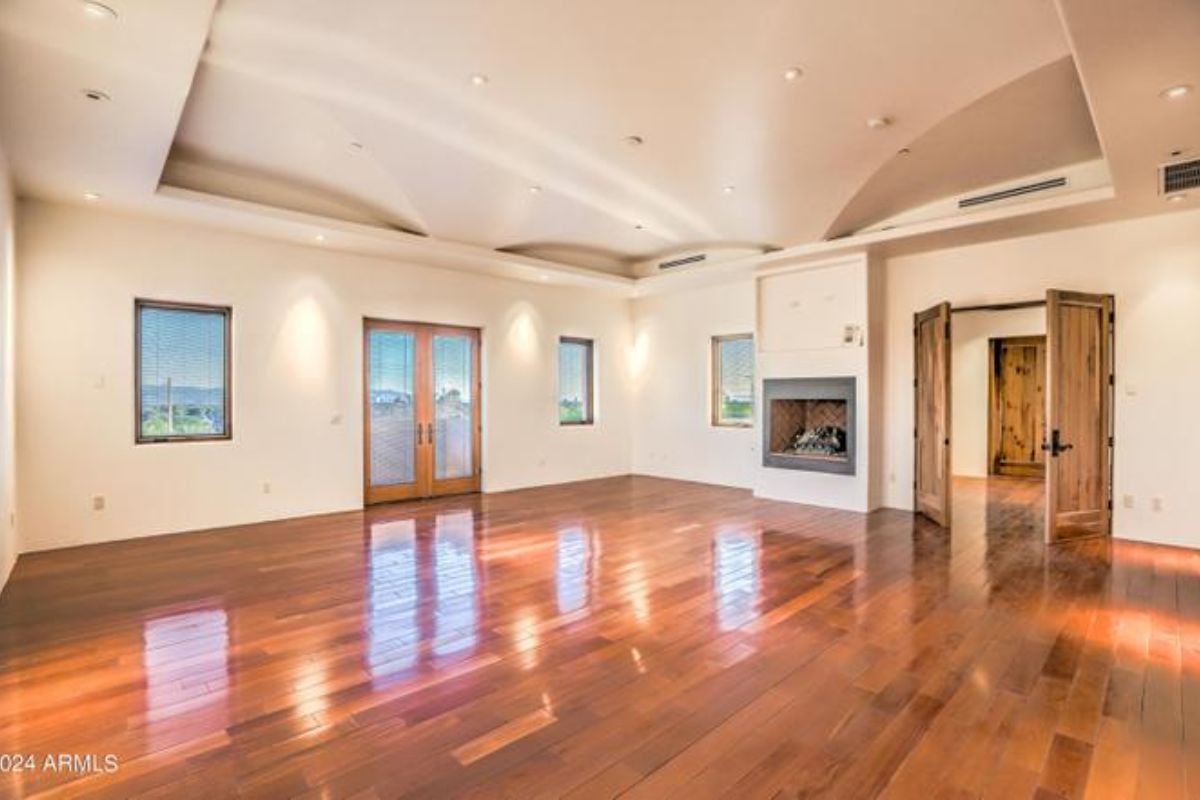 A living room with a fireplace, windows, and wooden floor.