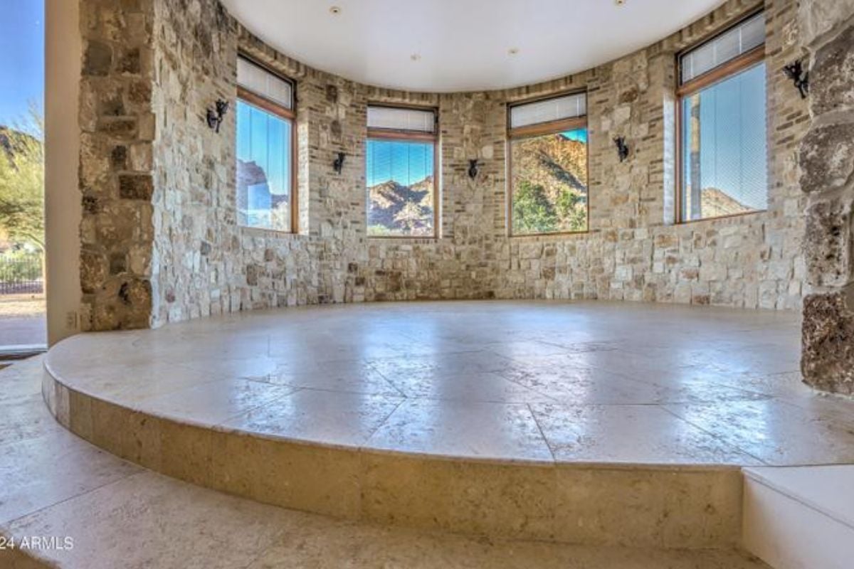 A sunroom with windows and stone walls.