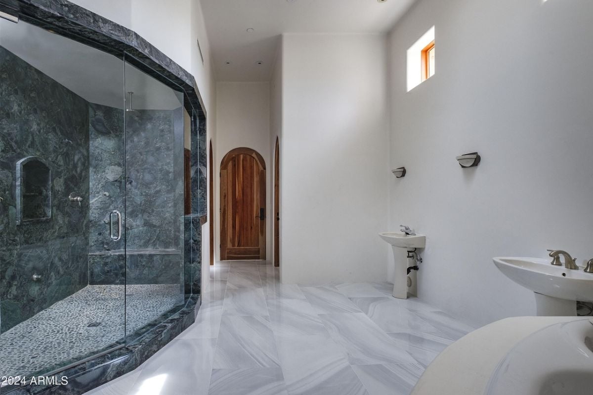 A bathroom with a tiled floor, vanity, and shower room.
