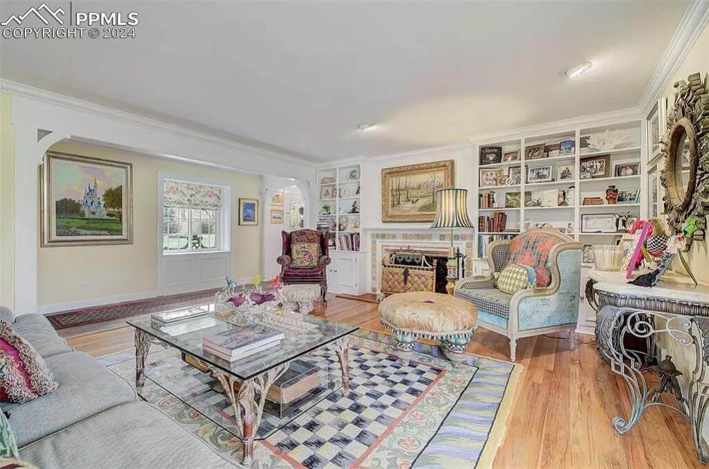 Living room with built-in shelves, wingback chairs, and a glass-top coffee table over the checkered area rug.