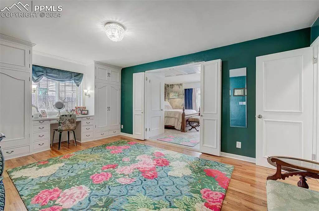 Primary office with a built-in desk a large floral rug that lays on the hardwood floor.