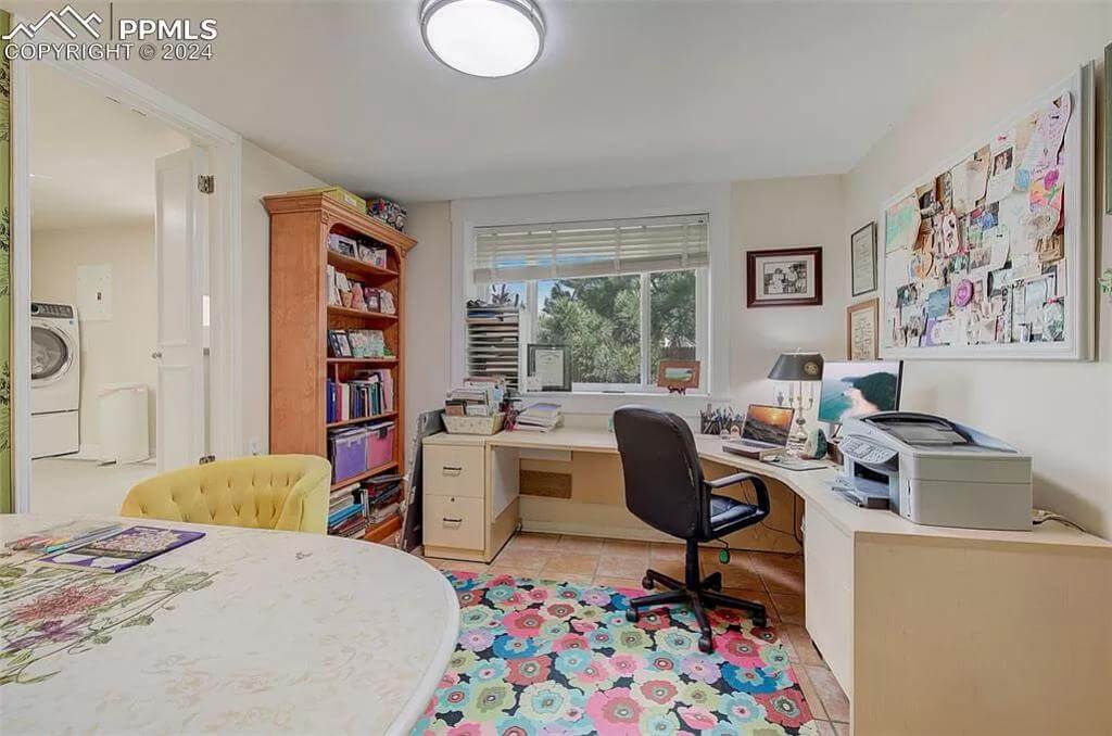 Office with an L-shaped desk and a swivel chair over the floral rug.