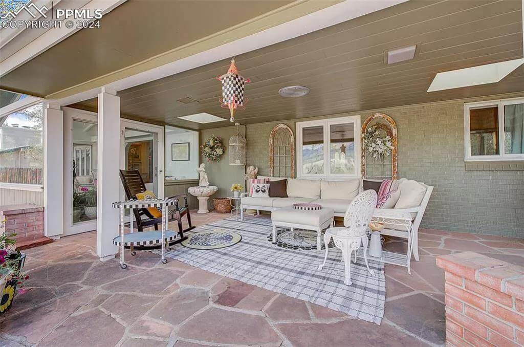 Covered porch with white ornate seats under the wood-paneled ceiling.