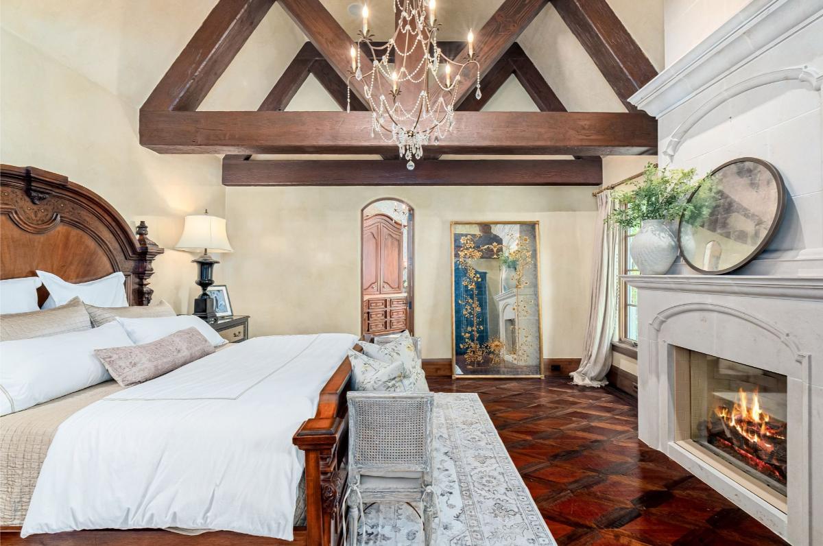 Bedroom with hardwood floors, vaulted ceiling and a fireplace.
