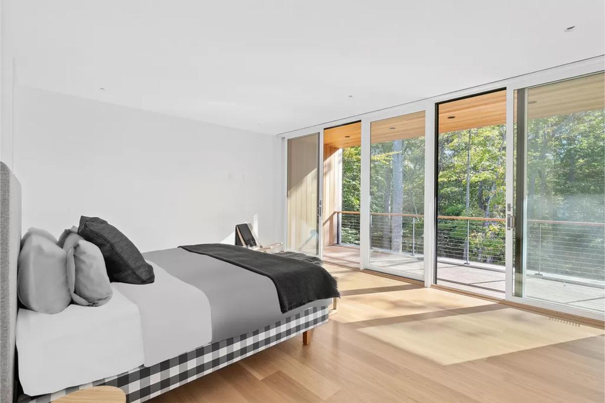 Bedroom with a hardwood floor, a large bed and sliding glass doors.