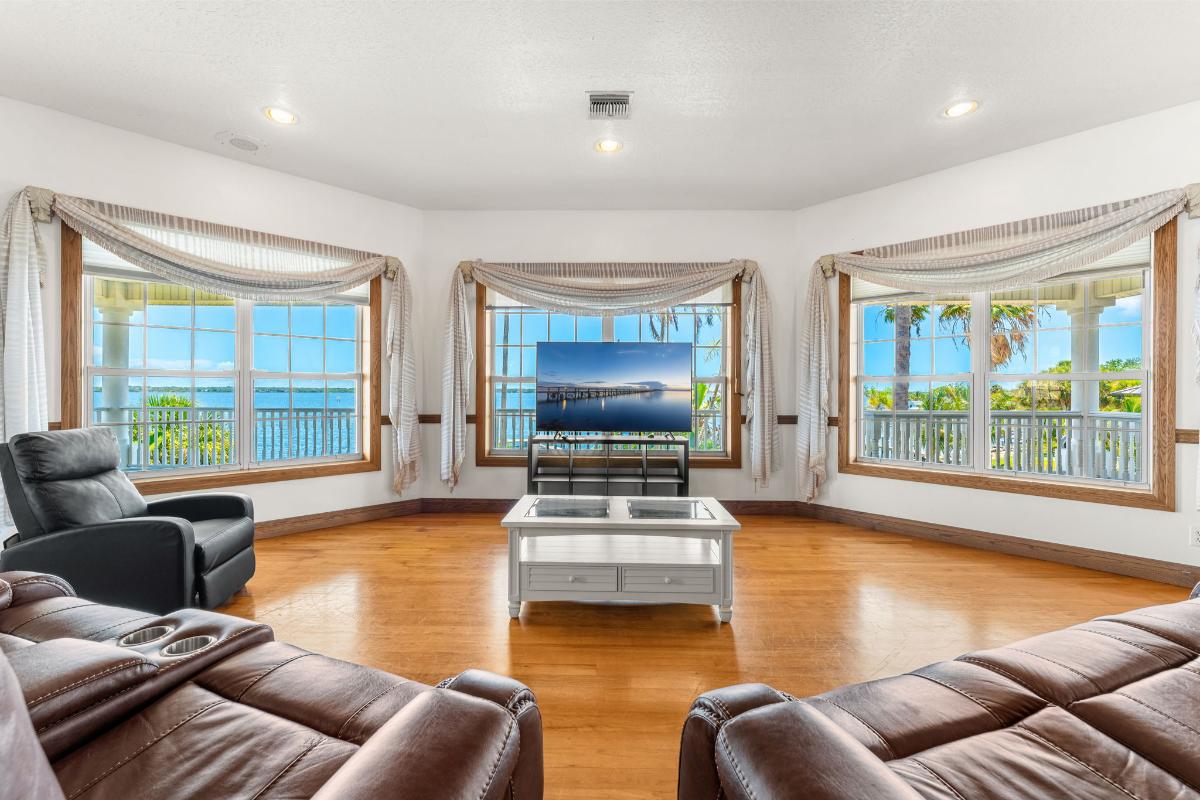 Living room with reclining chairs, TV and glass windows.