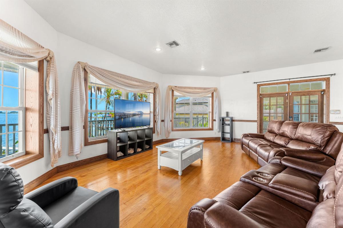 Living room with reclining chairs, TV and glass windows.