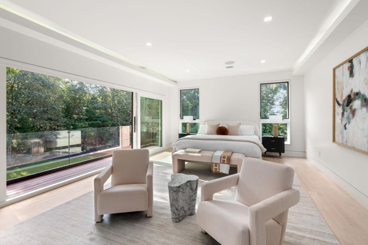 Bedroom with hardwood flooring, sliding glass doors and glass windows.