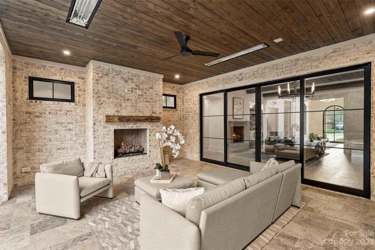 Covered patio with couches and a fireplace.