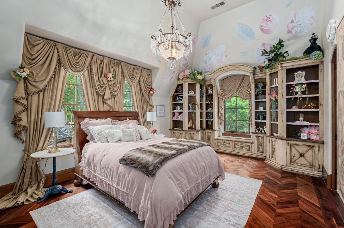 Bedroom with a large bed, chandelier and hardwood floors.