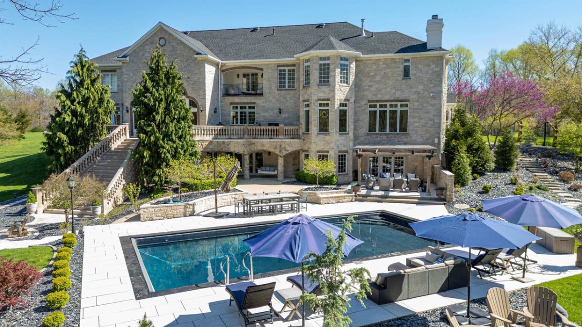 Rear view of the mansion with a pool, patio and a pergola.