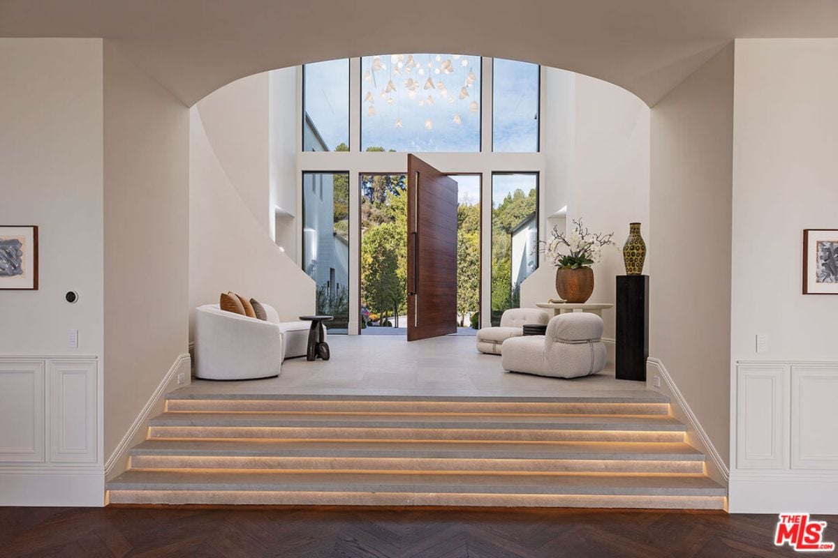A foyer with a chandelier, couches, and a table with a vase.