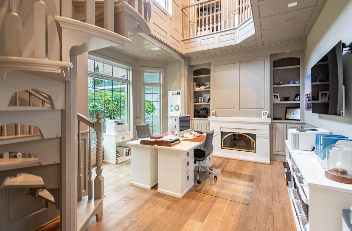 Home office with intricate wainscot moldings, a spiral staircase and a fireplace.
