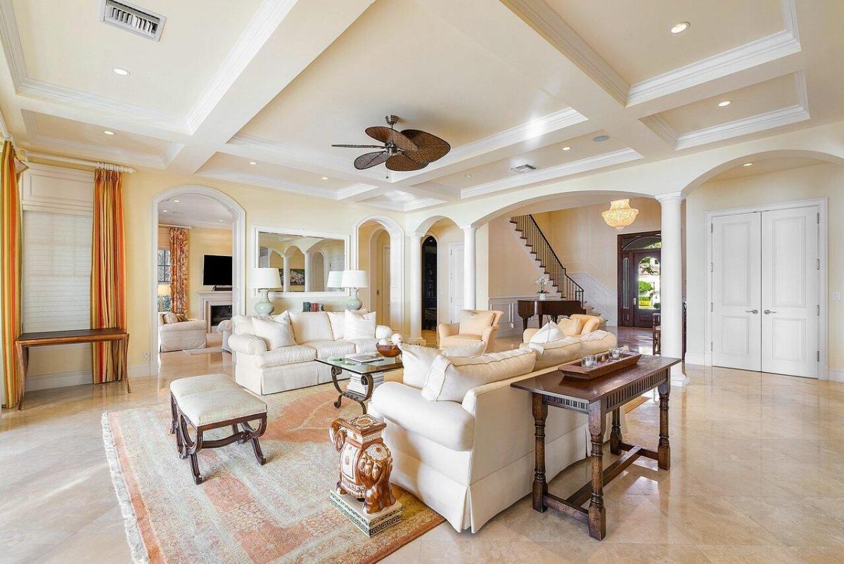Living room with marble flooring, coffered ceiling and custom lighting.
