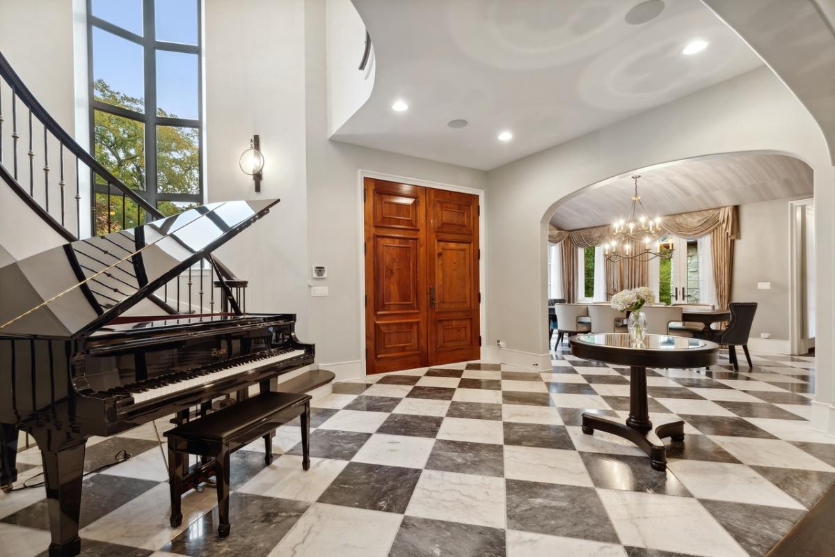 Foyer with hardwood door, wood table and a piano.
