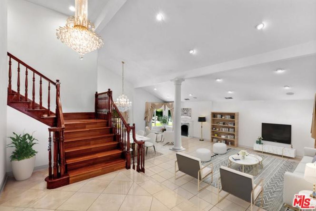 A foyer with a tiled floor, chandelier, and staircase.